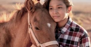 A young girl hugging a horse